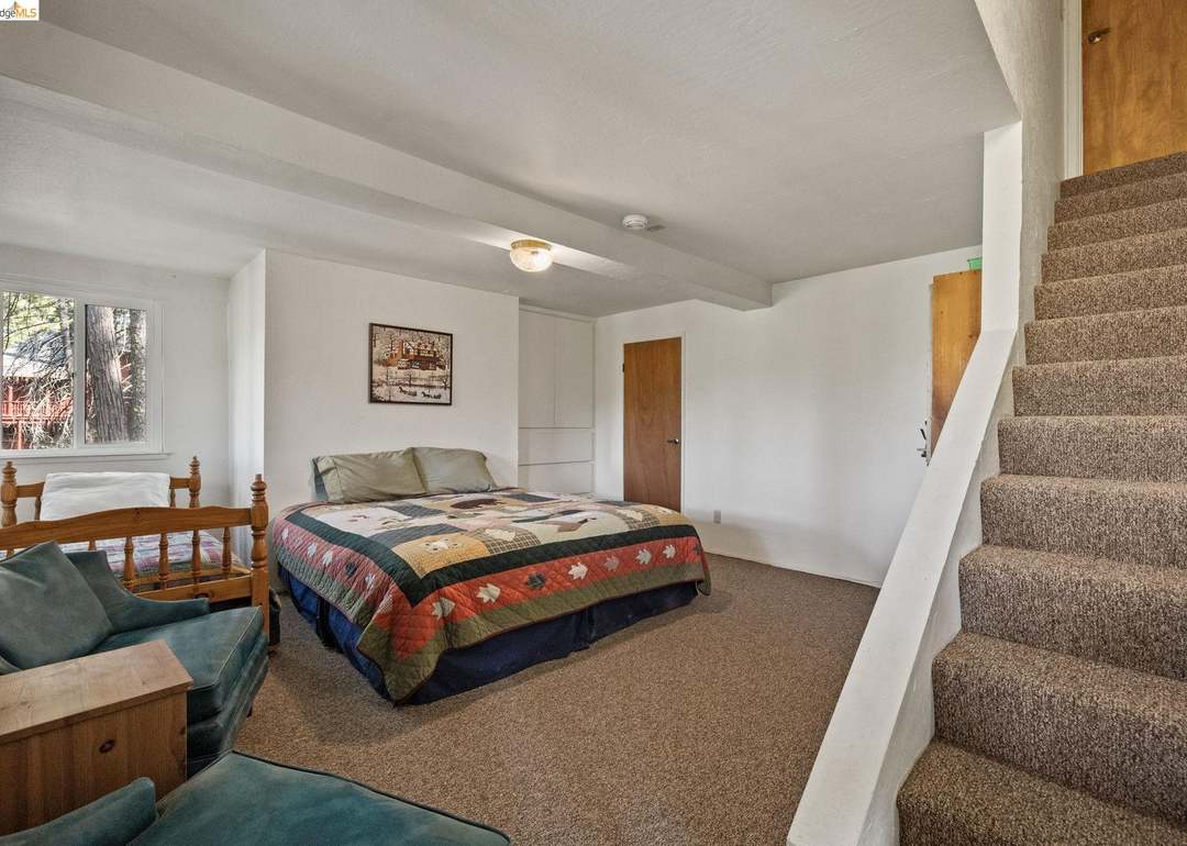 Bedroom with quilt bed and forest view windows